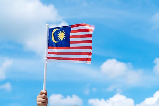 Happy young woman in hijab holding Malaysian flag during Malaysia Day in Putrajaya, Malaysia