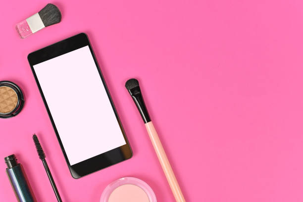 istock Flat lay with blank black smart phone with empty white screen and  makeup beauty products on pink background 1264245019