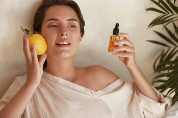 cuidado de la piel. retrato de belleza de la mujer sosteniendo limón y botella cerca de la cara. producto cosmético natural para derma facial saludable hidratado. aceite esencial y vitamina c para la terapia antienvejecimiento. - vitamin c fotografías e imágenes de stock