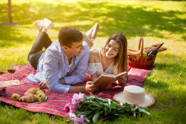 istock Beautiful married couple reading book while lying on picnic blanket in park 1264246936
