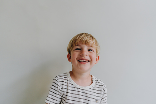 Photo of a smiling blonde boy; studio shot, isolated on a white background.