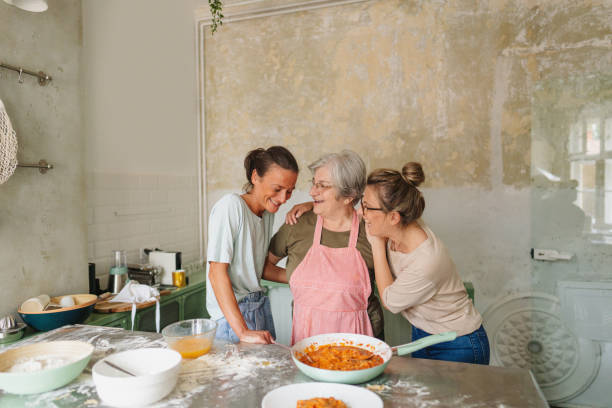 Making mom's authentic pasta Photo of a smiling senior woman and her daughters making homemade pasta in the kitchen; enjoying precious time together while cooking. mom and sister stock pictures, royalty-free photos & images