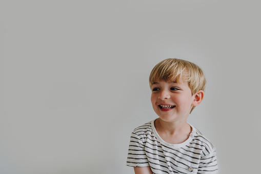 Photo of a smiling blonde boy; studio shot, isolated on a white background.