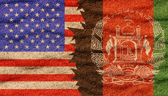 Afghan and American nafghan, ational flags on the sand surface