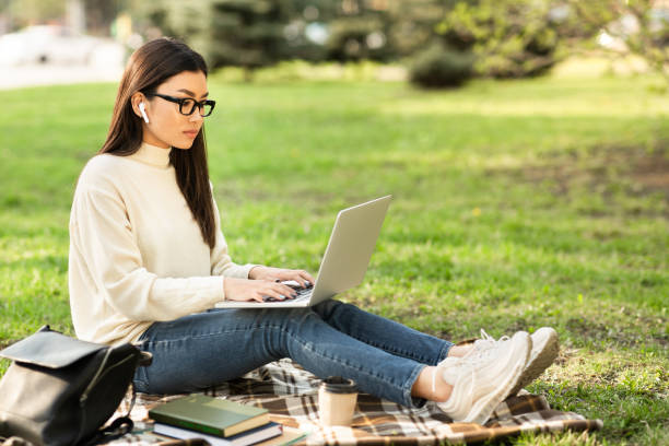 istock Asian woman using laptop, working in the park 1264250898