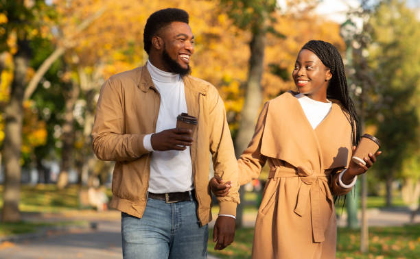istock Young afro couple having coffee while walking in autumn park 1264256229