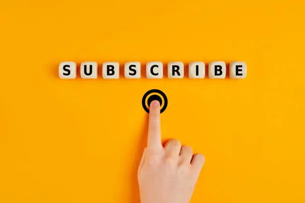 Photo of Male hand pressing subscription button with the word subscribe written on wooden blocks. Concept of online registration.