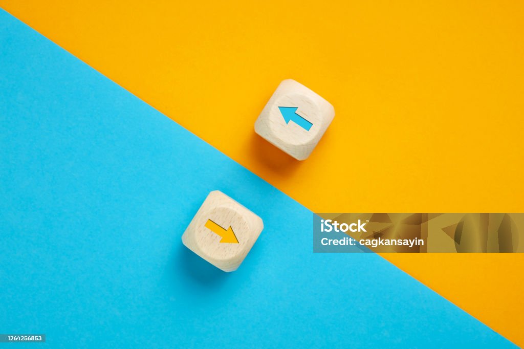 Arrow icons in contrast on wooden cubes moving towards opposite directions. Competition, diversity, opposition or confrontation concept. Contrasts Stock Photo