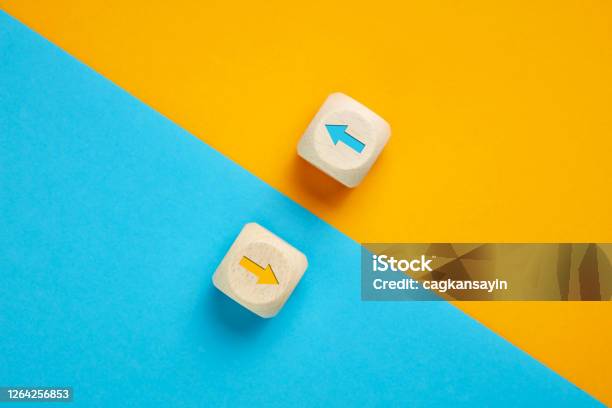 Arrow Icons In Contrast On Wooden Cubes Moving Towards Opposite Directions Competition Diversity Opposition Or Confrontation Concept Stock Photo - Download Image Now