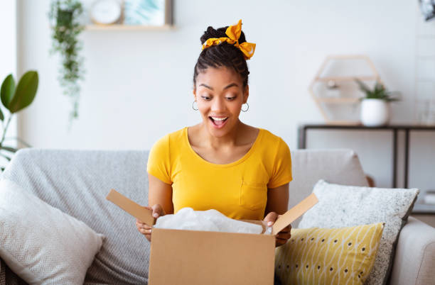 fille heureuse déballant des vêtements après le magasinage en ligne - unboxing activité photos et images de collection
