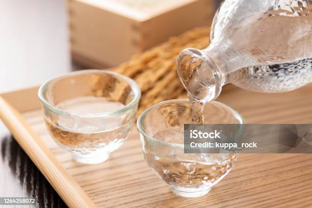 Cold Sake With Rice And Ear Of Rice On The Table Stock Photo - Download Image Now - Saki, Sake Brewery, Alcohol - Drink