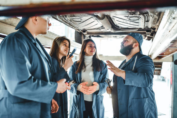 mechanic students learning about car parts underneath car with teacher - trainee mechanic engineer student imagens e fotografias de stock