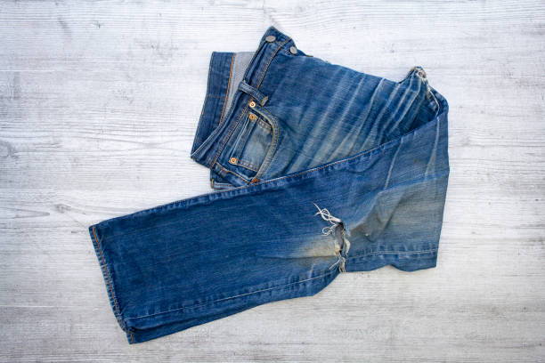 Denim texture.Blue jeans with threads and holes for the background
