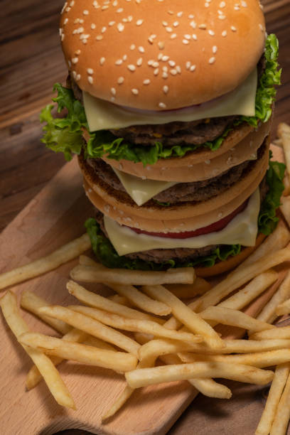 hamburguesa apilada sobre un fondo de mesa oscuro - grasa saturada fotografías e imágenes de stock