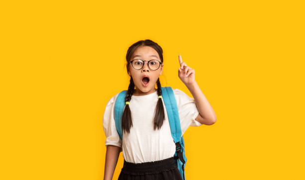 studentessa puntando il dito con l'idea di stare su sfondo giallo - moving up child pointing looking foto e immagini stock