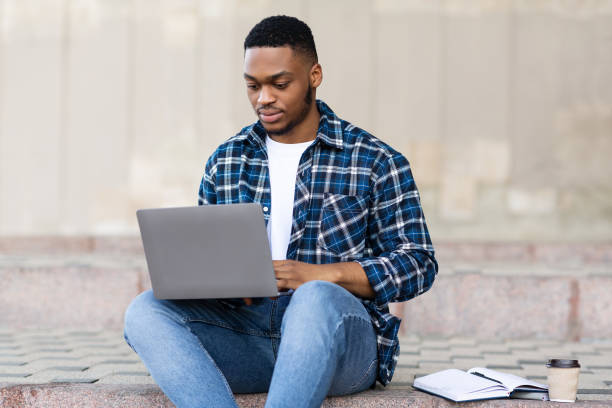 istock Student using laptop, sitting on the border in city 1264268570