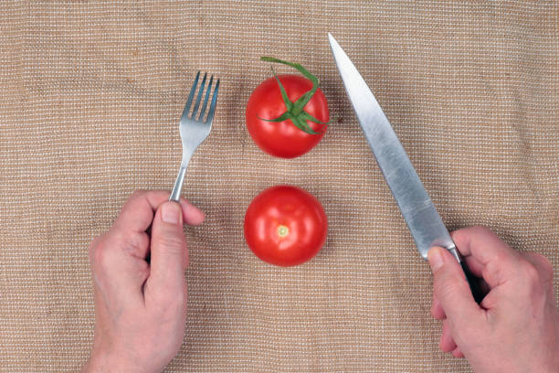 Elderly village man eating tomatoes with a knife and fork