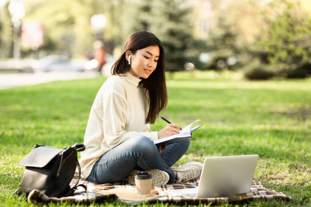 chica escribiendo en diario, sentado en un parque cerca de la universidad - filipino ethnicity audio fotografías e imágenes de stock