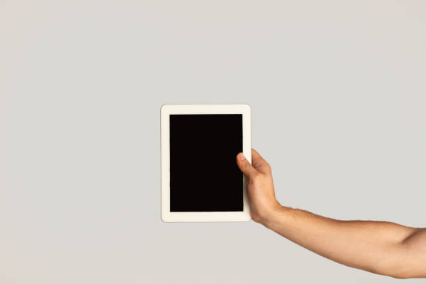 istock Millennial guy showing tablet with blank screen on light background, mockup for website design 1264269700