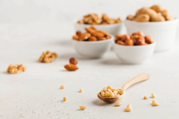 istock A handful of pine nuts in a wooden spoonl, assorted nuts on a light background. Healthy snacks, healthy fats. Copy space 1264269744