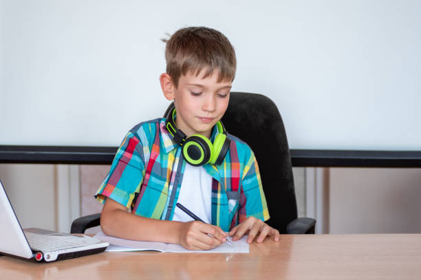 istock A cute boy is sitting at the table, writing homework or preparing for an exam. Concept Back to school 1264278582