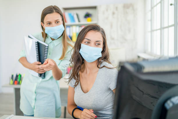 istock Colleagues in the office working while wearing medical face mask during COVID-19 1264279327