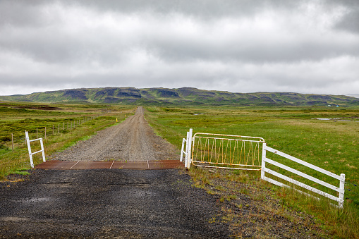 Road with a cattle grid in a typical Icelandic landscape under an impressive cloudscape