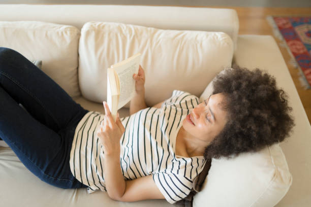 istock Afro american female relaxing at home reading a book 1264281824