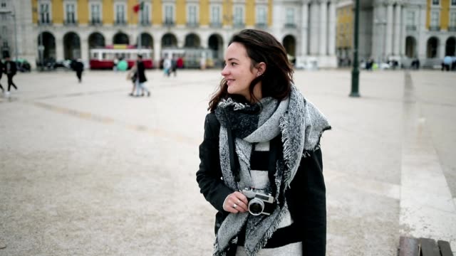 Smiling pensive tourist girl wearing overcoat and scarf