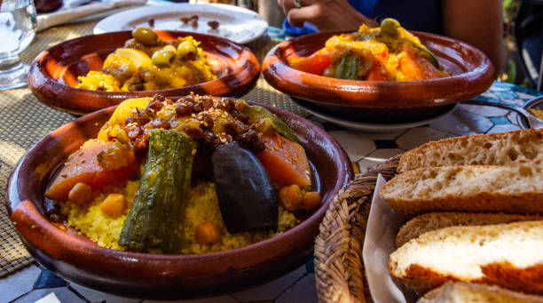 Couscous dish on a family table Couscous (Arabic: كُسْكُس‎ ) is a Maghrebi dish of small (about 3mm diameter) steamed balls of crushed durum wheat semolina, usually served with a stew spooned,vegetables at family gatherings. fez morocco stock pictures, royalty-free photos & images