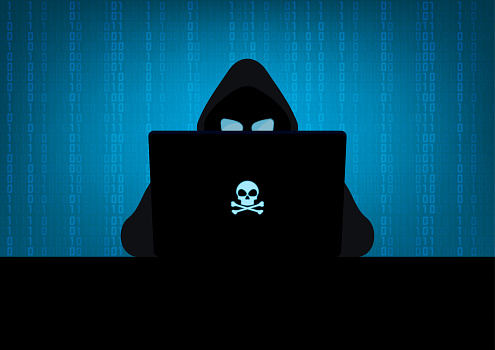 Silhouette of hacker wearing hood using laptop computer with glow in the dark blue skull and crossbones logo in dark room on blue binary code number background
