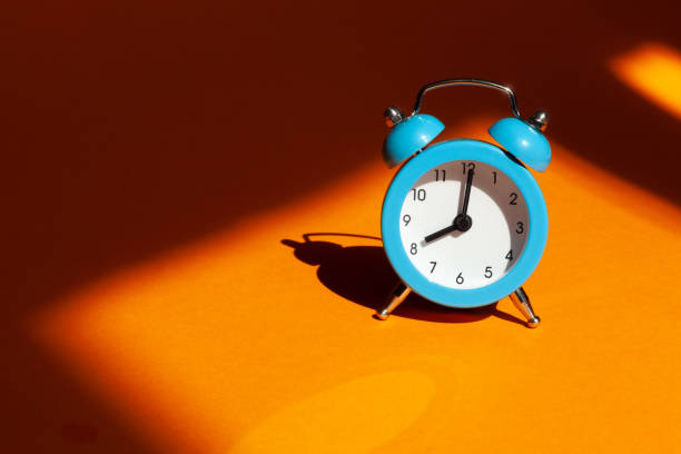 Blue alarm clock on orange background. Wake up alert Morning concept. stock photo