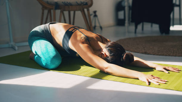 Yoga can help you move better and feel less stiff Shot of a young woman practicing yoga at home childs pose stock pictures, royalty-free photos & images