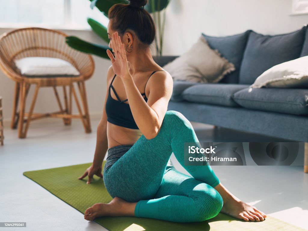 She has amazing flexibility Shot of a young woman practicing yoga at home Twisted Stock Photo