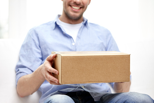 delivery, mail and people concept - happy smiling man with cardboard box or parcel at home