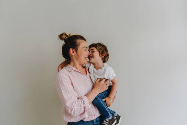 Love Portrait of a smiling young woman holding her son; studio shot, over the gray background. i love you photos stock pictures, royalty-free photos & images