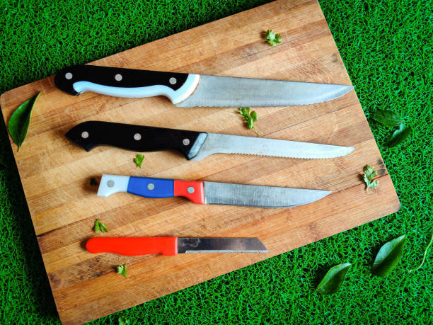 istock Four colored different sizes of knives kept on chopping board. With curry leaves and coriander leaves spread around 1264306036