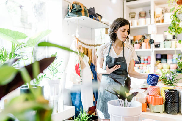 flower shop worker using digital tablet - owner boutique store retail imagens e fotografias de stock