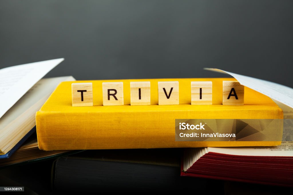 The concept of useless knowledge with books. The concept of trivia knowledge. Trivia word from wooden blocks with letters on old and new books are piled up in a careless pile for uselessness, Much knowledge Trivia Stock Photo