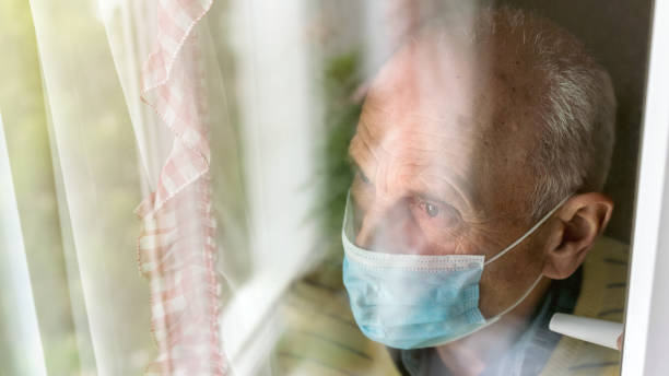 istock old man in blue disposable mask stands near window 1264309374