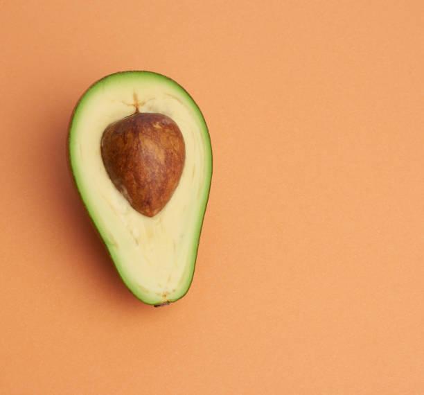 istock half ripe green avocado with a brown bone on an abstract orange background 1264314995