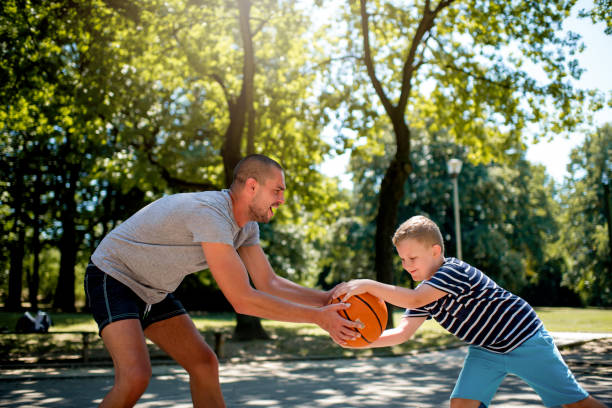 istock Cute blond boy practicing basketball with his coach 1264317548
