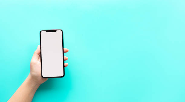 istock Female hand showing smartphone with blank screen on color background 1264318346