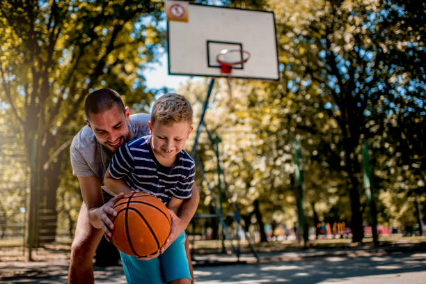 istock Cute blond boy practicing basketball with his coach 1264318381