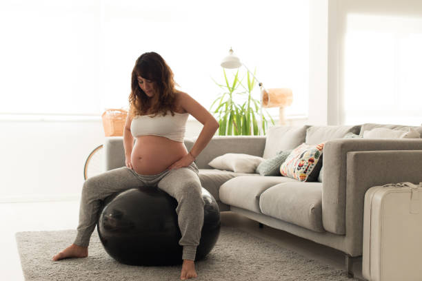 Pregnant woman doing relax exercises with a fitball Pregnant woman doing relax exercises with a fitness pilates ball at home fitness ball photos stock pictures, royalty-free photos & images