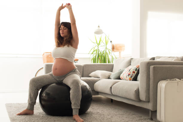 schwangere frau macht entspannungsübungen mit einem fitball - human pregnancy exercising relaxation exercise sport stock-fotos und bilder