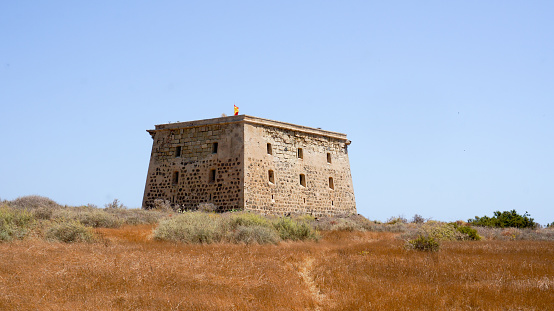 Alicante, Spain - July, 2020: View to ancient fort watch tower in summer time on Tabarca Isle, clear blue sky background, used also as a prison.