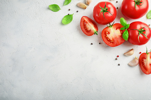 Fresh ripe tomatoes, garlic and herbs on white background. Top view. Copy space.