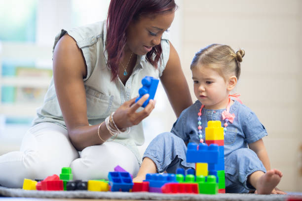 istock Daycare teacher builds blocks with toddler 1264323536