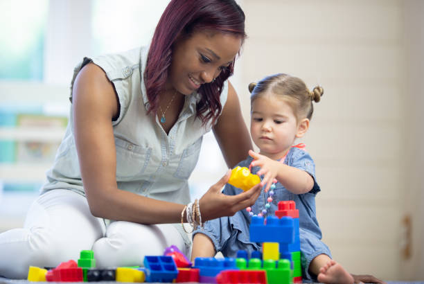 istock Daycare teacher builds blocks with toddler 1264323538